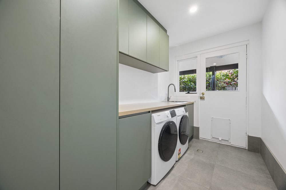 Laundry with green cabinetry, washer and dryer